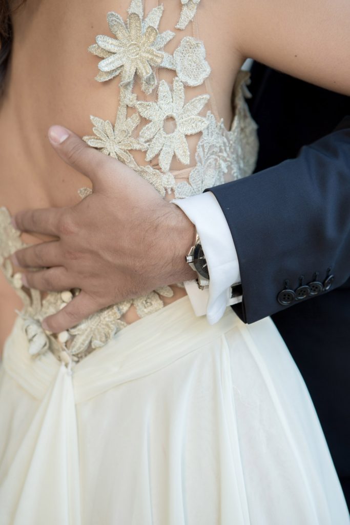 Romantic bride and groom portrait framed by soft greenery, captured against a rustic stone wall in a sun-washed Mediterranean setting. Their warm smiles and tender gaze create an intimate, timeless moment—perfect for destination wedding photography in a charming historic village.