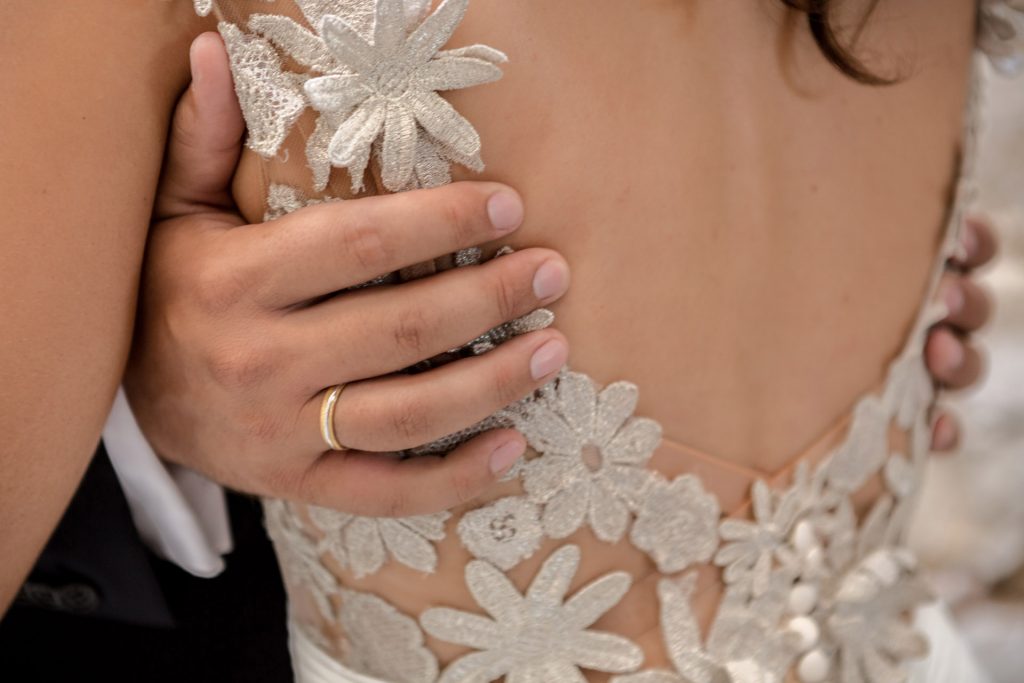 Romantic bride and groom portrait framed by soft greenery, captured against a rustic stone wall in a sun-washed Mediterranean setting. Their warm smiles and tender gaze create an intimate, timeless moment—perfect for destination wedding photography in a charming historic village.