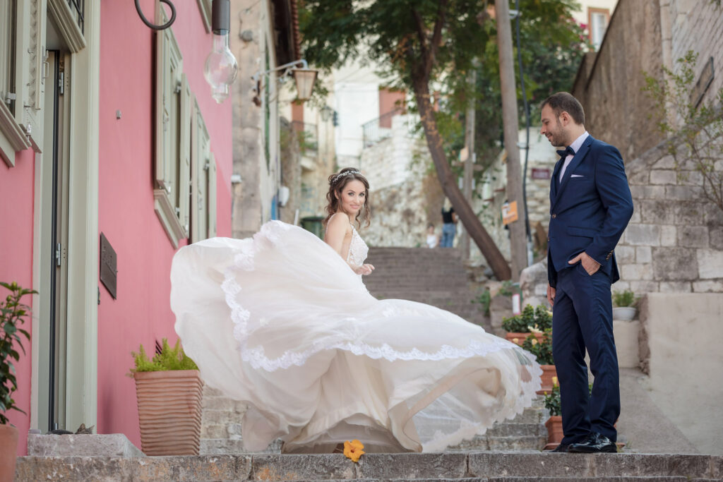 Bride twirling wedding dress groom watching charming street Nafplio old town Greece destination wedding photography