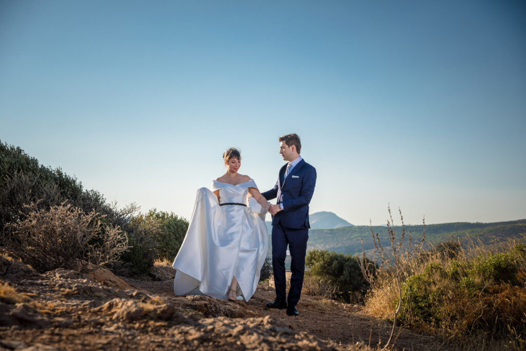 Bride and groom dramatic hilltop portrait dress flowing Cape Sounion Attica Greece coastal landscape destination wedding photography