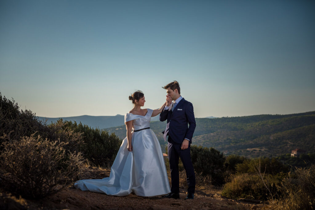 Bride and groom dramatic hilltop portrait dress flowing Cape Sounion Attica Greece coastal landscape destination wedding photography