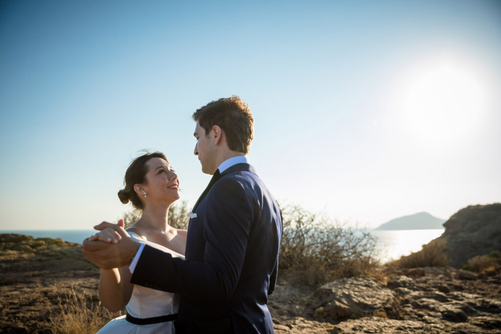 Bride and groom dramatic hilltop portrait dress flowing Cape Sounion Attica Greece coastal landscape destination wedding photography