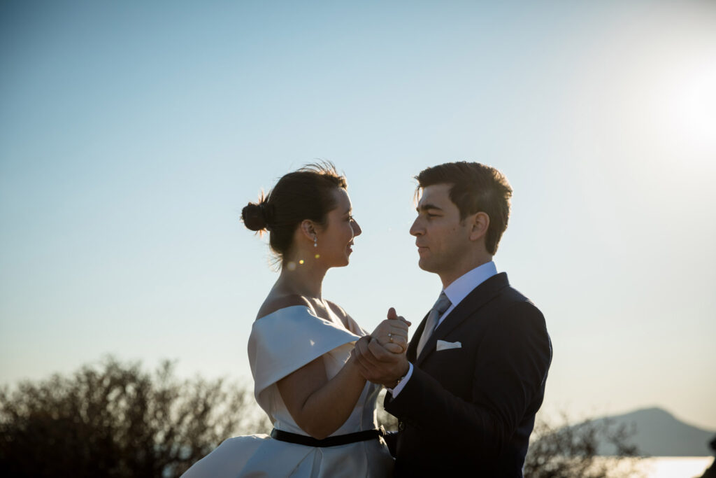 Bride and groom dramatic hilltop portrait dress flowing Cape Sounion Attica Greece coastal landscape destination wedding photography