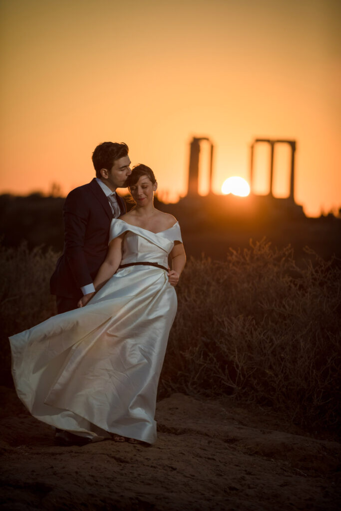 Bride and groom dancing sunset Temple of Poseidon Cape Sounion Greece ancient columns coastal landscape destination wedding photography