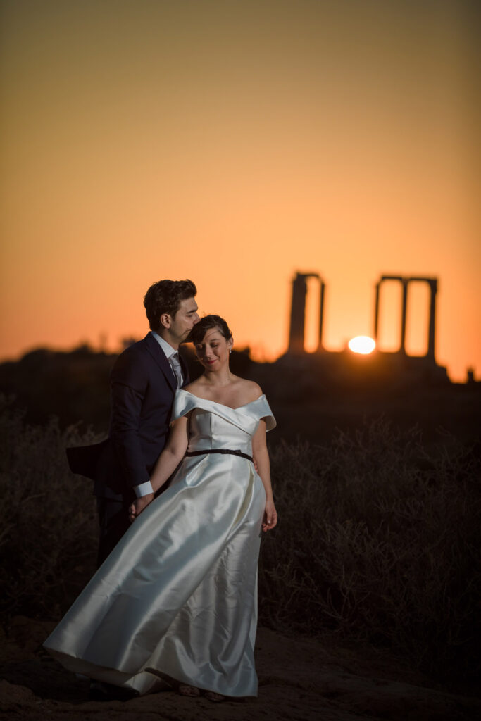 Bride and groom dancing sunset Temple of Poseidon Cape Sounion Greece ancient columns coastal landscape destination wedding photography