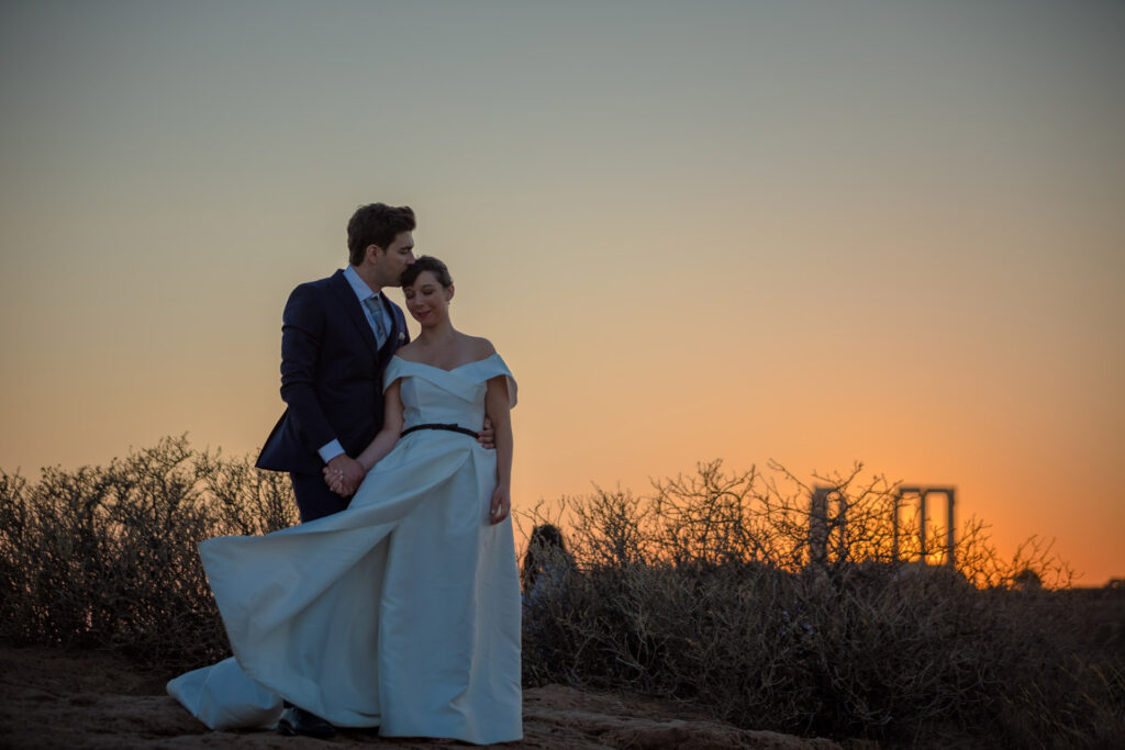 Bride and groom dancing sunset Temple of Poseidon Cape Sounion Greece ancient columns coastal landscape destination wedding photography