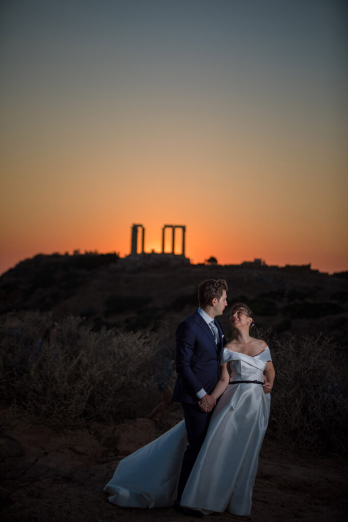 Bride and groom dancing sunset Temple of Poseidon Cape Sounion Greece ancient columns coastal landscape destination wedding photography
