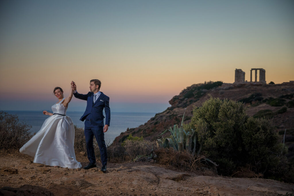 Bride and groom dancing sunset Temple of Poseidon Cape Sounion Greece ancient columns coastal landscape destination wedding photography
